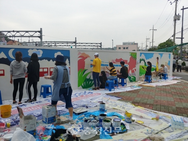 지난 16일 신탄진동 주민과 대학생 자원봉사자 철도담장 위를 달리는 열차벽화를 그리기 위해 밑그림 작업을 하고 있다.