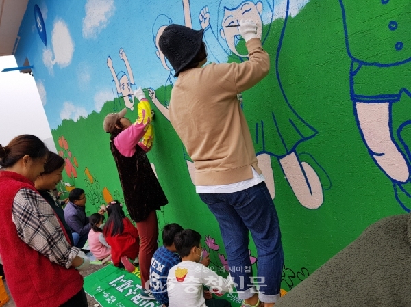 백운초 학생과 교직원, 학부모들이 학교 외벽에 벽화를 그리며 즐거워하고 있다.