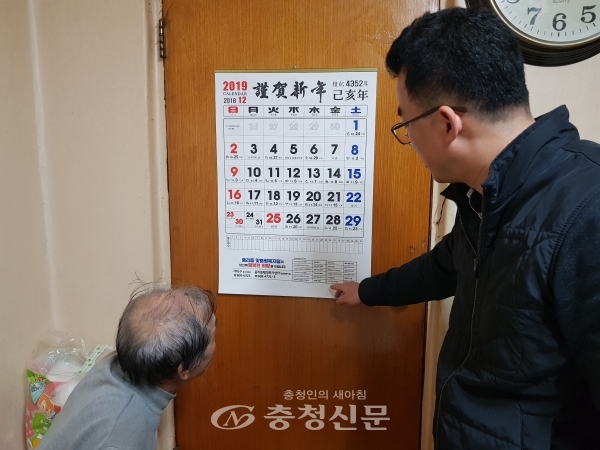 중리동주민센터 사회복지담당 김기석 주무관(오른쪽)이 홀몸 어르신 세대를 방문해 복지달력을 달아 드리고 설명하고 있는 모습.