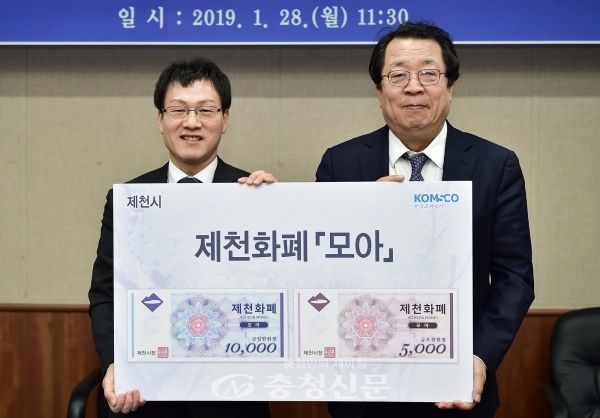 이상천 제천시장(오른쪽)이 한국조폐공사 황문규 기술 해외 이사로부터 제천화폐 도안을 넘겨받고 기념촬영을 했다.
