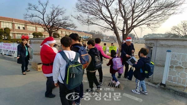 산타 모자를 쓴 유경균 교육장(오른쪽)이 등교하는 학생들에게 간식을 나누어주고 있다.