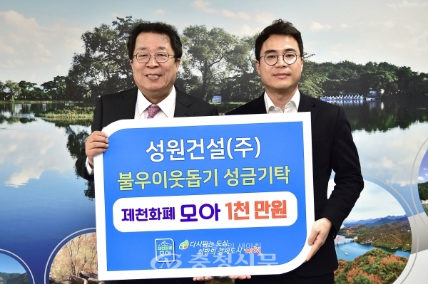 장태순 성원건설 대표(오른쪽)가 이상천 제천시장에게 성금을 전달하고 기념촬영을 했다.