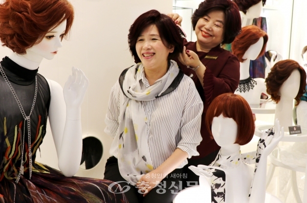 롯데백화점 대전점 헤어웨어 브랜드 씨크릿우먼 매장에서 여성 고객이 볼륨형 입체적 구조를 가져 두상 성형 효과를 제공하는 헤어웨어를 체험하고 있다. (사진=롯데쇼핑 제공)