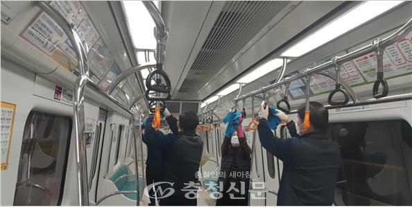 대전도시철도 직원들이 소독용 에탄올을 사용하여 전동차 내 손잡이와 지지봉을 소독하고 있다.(사진=대전도시철도 제공)