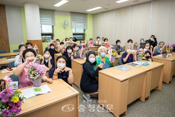 진천여중 학생들이 꽃바구니를 전달하고 문해학교 어르신과 하트를 그려 보이고 있다. (사진=증평군 제공)