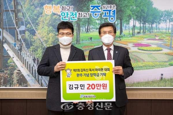 김규민 씨(왼쪽)가 완주 기념으로 20만원의 장학금을 전달하고 홍성열 군수와 기념 촬영하고 있다. (사진=증평군 제공)
