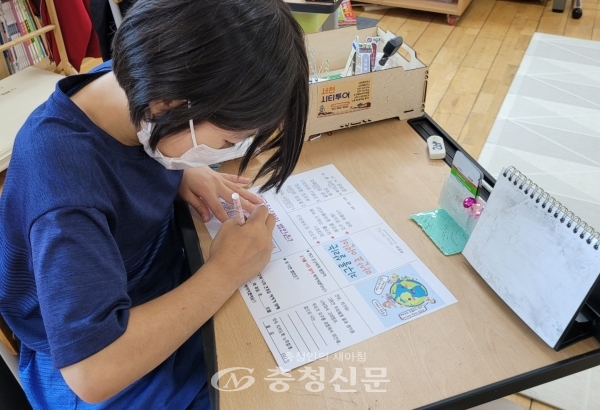 마산초등학교 어린이가 미니북에 지구와 나의 건강을 지키는 실천 의지를 적고 있다..jpg