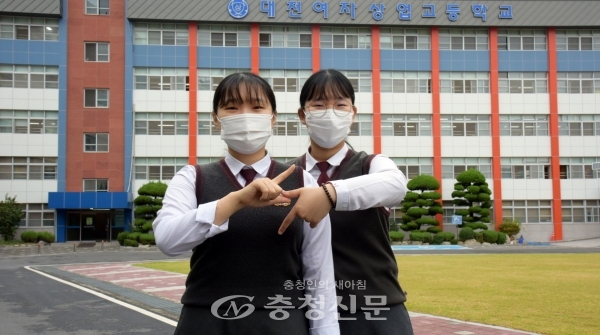 한국전력공사에 최종합격한 대전여상 3학년 최예리, 지민영 학생이 한전의 '전기'를 상징하는 모양을 만들어 보이고 있다.(사진=대전여상 제공)
